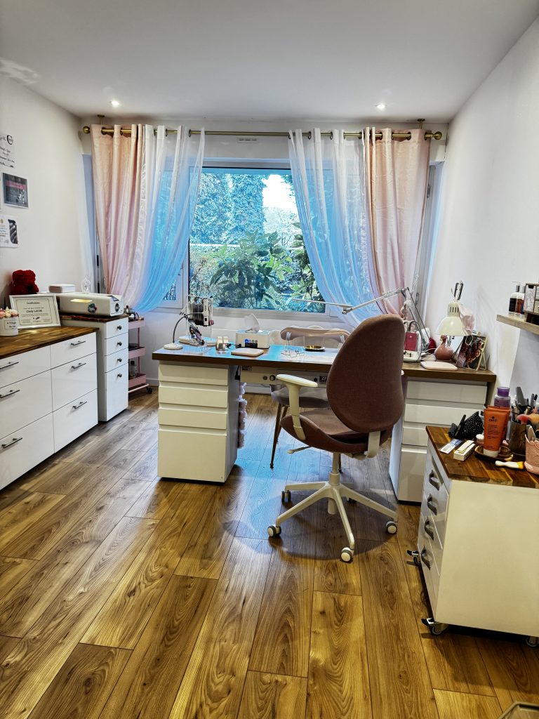 photo du salon, composé d'un bureau et d'un meuble bas . Vue sur une baie vitrée avec des rideaux rose